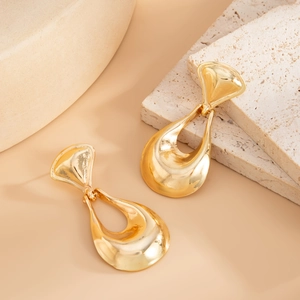 Detail shot of hollow golden liquid lava earrings on a natural stone background