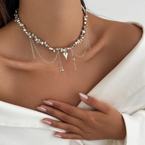 Detail of silver heart charm necklace with multi-layer chains on model's neckline