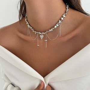 Detail of silver beaded necklace featuring a heart pendant and long chain tassels on a model