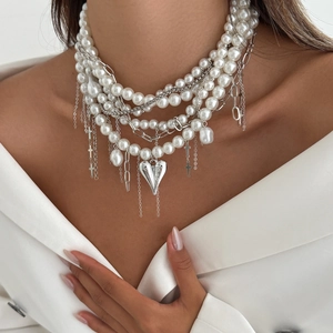 Detail of layered pearl necklace with heart pendant and silver cross on model