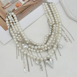 Detailed view of layered pearl necklace with silver heart and cross charms on white texture