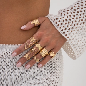 Detail showing stacked gold starfish and seashell rings set with coral texture