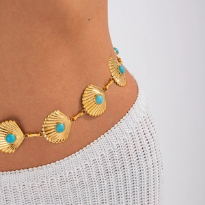 Detailed shot of golden shell body chain with turquoise inlay on white crochet skirt