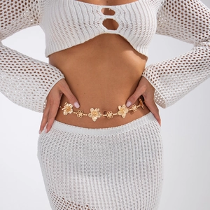 Close-up of golden 18K metal waist chain with 3D flower petal charms on white dress