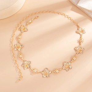 Close-up of golden alloy waist chain featuring intricate floral metal charms and long shadows