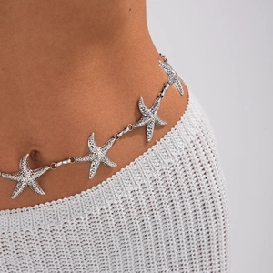 Detailed view of silver alloy starfish waist chain on model with knit white dress