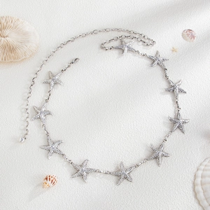 Ocean style silver starfish waist chain on white sand with sea shells and corals