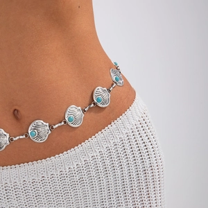 Detail of bohemian silver waist chain with shell links and turquoise beads on model