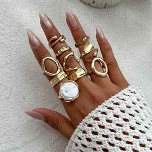 Golden geometric ring set featuring irregular textures and pearl accents on fingers