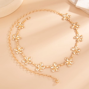 Luxurious gold flower body chain jewelry on minimalist stone display for women