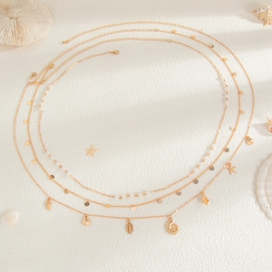 Detail of gold starfish and shell waist chain with pearls on beach sand background