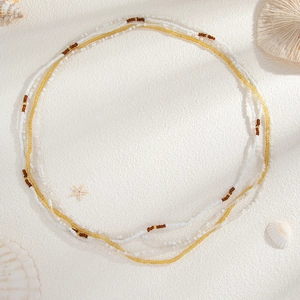 Détail de perles colorées et coquillages sur sable pour bijoux de corps bohème