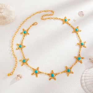 Détail d'une chaîne de taille étoile de mer dorée rétro avec des touches turquoise