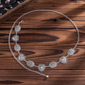 Detail of vintage silver bohemian body chain featuring heart and sunburst metal medallions
