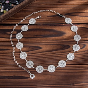 Close-up of bohemian silver waist chain with 11 hollowed-out metal circles on wood