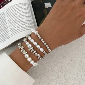 Silbernes Perlenarmband-Set mit weißen Perlen und Herz-Quastenanhänger am Handgelenk