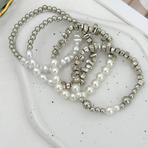 Detail von silbernen Metallperlen und weißen Perlen in einem 4-teiligen Armband-Set