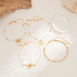 Detail of 5-piece beach anklet set featuring shells and starfish on textured background