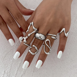 Close-up of irregular fluid silver rings with wave and lava patterns on a white background