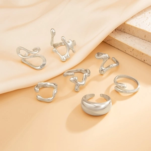 Detailed view of 7-piece silver geometric irregular fluid rings on soft silk and stone