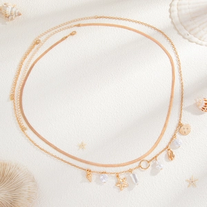 Golden double-layer body chain with starfish, seashells, and pearls on a beach sand background