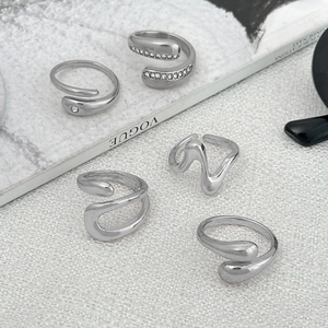 Set of five silver adjustable rings with wave patterns and zircon stones on white background