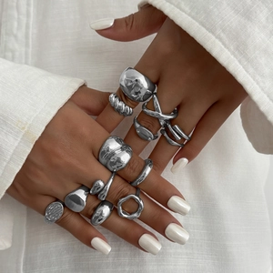 Close-up of stacked silver water drop rings with irregular molten textures and geometric shapes