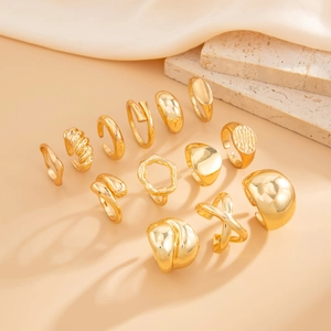 Detail view of 13-piece gold geometric ring set with textured surfaces on elegant fabric