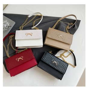 Détail de quatre sacs à chaîne en blanc, beige, bordeaux et noir avec boucles en nœud