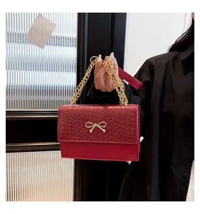 Détail du sac rouge carré avec rabat tressé et fermoir nœud en métal doré