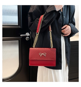 Détail du sac bandoulière rouge avec fermoir nœud doré et bandoulière chaîne