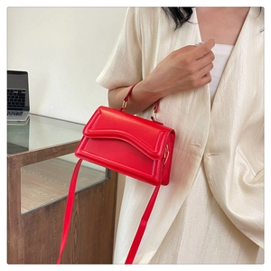Détail du sac à main carré rouge avec rabat ondulé et finitions métalliques dorées