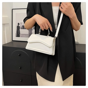 Elegant white glossy leather handbag for women featuring a unique wavy flap and crossbody strap