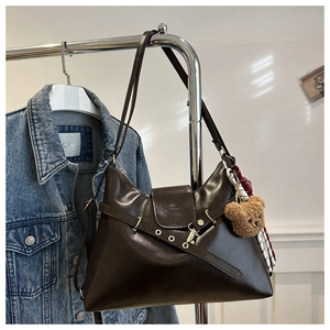Detail view of a dark brown PU leather tote bag with teddy bear charm and metal eyelets