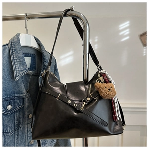 Detail of black faux leather tote with gold ring buckle and cute bear pendant charm