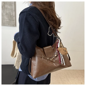 Detail of vintage brown leather hobo bag with teddy bear charm and fashion leather stamp