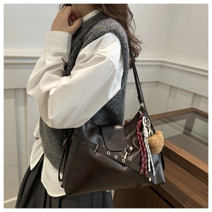 Detail of vintage brown PU leather tote with metal buckle and cute bear pendant