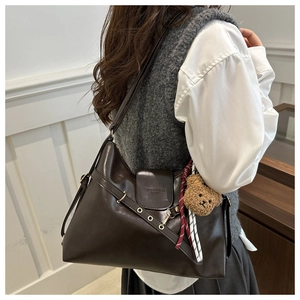 Brown vintage PU tote bag with bear charm shown on model in a stylish interior setting