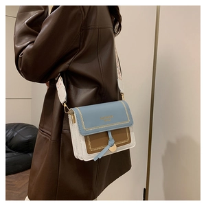 Detail view of contrast color crossbody bag with stylish wide woven shoulder strap