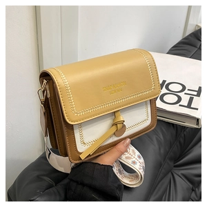 Close-up of tricolor square crossbody bag with embroidered strap on a leather sofa