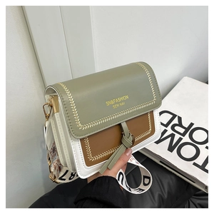 Detail of color-block crossbody bag with gold wheat stitching and wide woven strap