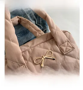 Close-up of pink quilted tote bag with golden bow hardware and soft padded texture