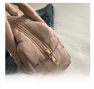 Detail shot of smooth gold metal zipper and diamond quilted pattern on pink tote bag