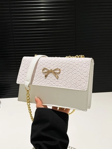 White woven leather crossbody bag with golden bow ornament and chain strap detail
