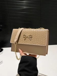 Khaki woven chain shoulder bag with golden bow ornament in a handheld studio display
