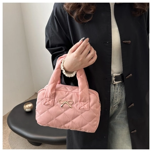 Detail of pink quilted handbag with golden bow metal buckle and wide carry handle