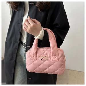 Detailed shot of pink quilted handbag with golden bow metal buckle and soft handle