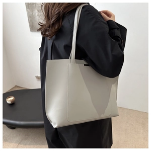 Light gray large tote bag with front pocket and long shoulder straps worn by model