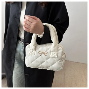Detail of white quilted tote bag with golden bow and elegant diamond stitching