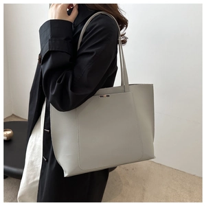 Detail of light grey leather tote bag featuring elegant metal buckle and long straps